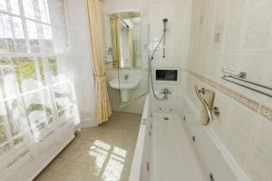 a white bathroom with a tub and a sink at Haddon House Hotel in Bridport +2 photos