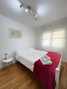 a bedroom with a bed with a red blanket and a table at Dalí City Apartamento in Figueres