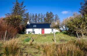 a white house with a red door in a field at The Cottage, 7 Struanmore in Struan