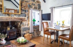 a living room with a stone fireplace and a table and chairs at The Cottage, 7 Struanmore in Struan
