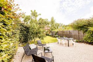 eine Terrasse mit Tisch und Stühlen in einem Garten in der Unterkunft Le Petit Hômage in Lanaken