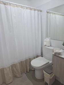 a bathroom with a toilet and a white shower curtain at Pacific blue cómodo y familiar in La Serena