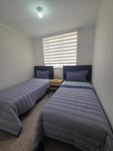 two beds in a room with a window at Pacific blue cómodo y familiar in La Serena
