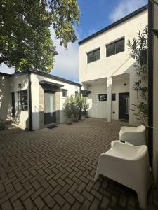 a courtyard with two white chairs and a building at Departamentos Galarza Alojamiento en Concepción del Uruguay in Concepción del Uruguay