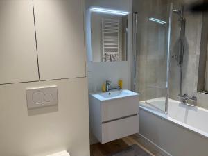 a white bathroom with a sink and a shower at Cosy Seahouse in Knokke-Heist
