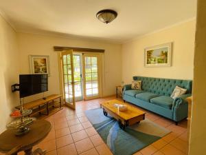 a living room with a blue couch and a tv at Villa Provence Estate in Pokolbin