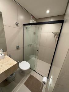 a bathroom with a toilet and a glass shower at Suítes Pousada Canaã in Araxá