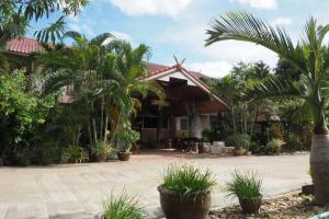 a house with palm trees in front of it at ภูตะวัน กาญจน์ รีสอร์ท Phutawan Kan Resort in Kanchanaburi City