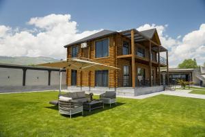 a wooden house with chairs and an umbrella at Wooden villa with superpool and sauna, 30 min from Yerevan in Tsakhkashen