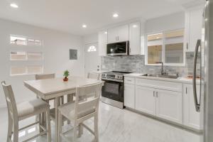 a kitchen with white cabinets and a table and chairs at 13 Mi to Universal Studios: Renovated Cottage! in Los Angeles