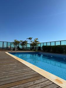 a swimming pool next to a wooden deck at Master Plaza Hotel in Barbacena