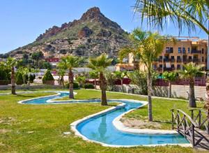 a resort with palm trees and a mountain in the background at Spa Valley II experiences Penthouse con Piscina climatizada y Yacuzzi in Villanueva de Río Segura
