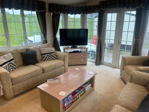 a living room with a couch and a tv at OV19- Wind in the willow summer house in Heysham