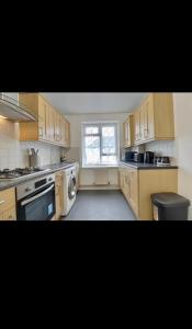 a large kitchen with wooden cabinets and a window at Flat in Portsmouth in Portsmouth +8 photos