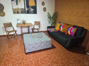 a living room with a black couch and a table at Sunset room in Aguada