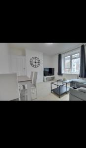 a living room with a table and a clock on the wall at Flat in Portsmouth in Portsmouth