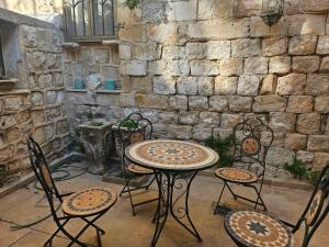 a patio with a table and chairs and a stone wall at בית האומן in Safed