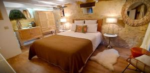 a bedroom with a large bed and a stone wall at Gîte Les Pierres Blondes in Groléjac
