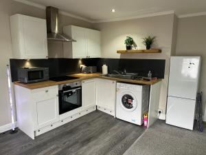 a kitchen with white cabinets and a washer at Modern 2 Bed Apartment, Sleeps 4 in Bolton