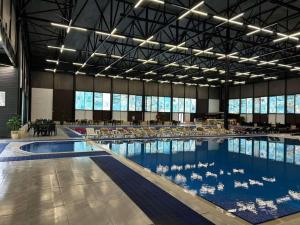 a large swimming pool with tables and chairs in a building at Aquapark Quba Hotel in Quba