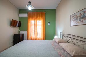 a bedroom with a bed and a window with an orange curtain at Delphian Colors - Orange Edition by Filos Inc in Delphi