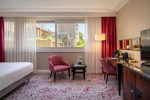 a hotel room with a bed and a desk and chairs at Warwick Paris Champs-Elysées in Paris +81 photos