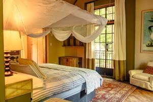 a bedroom with a canopy bed and a window at The River Villa in Magaliesburg
