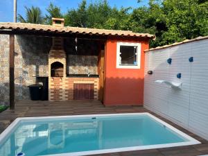 a swimming pool in a backyard with a house at Casa de Praia no Condomínio Florestinha com 02 quartos in Tamoios