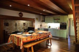 a kitchen with green cabinets and a table with a table cloth at Gîte avec jardin pour 6 pers près de Salers Nature & Puy Mary in Le Vigean