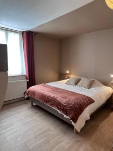 a bedroom with a large bed and two windows at Le Verger in La Charmée