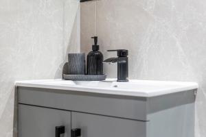 a white bathroom sink with a soap dispenser on it at Modern 2-Bed Apartment 30 mins from Central London in Finchley +44 photos