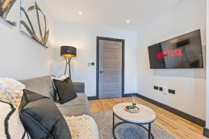 a living room with a couch and a tv on a wall at Modern 2-Bed Apartment 30 mins from Central London in Finchley