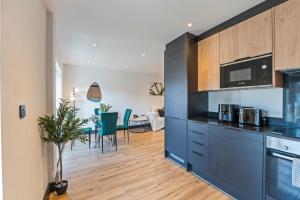 a kitchen with black cabinets and a dining room at Modern 2-Bed Apartment 30 mins from Central London in Finchley