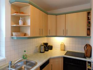 a kitchen with wooden cabinets and a sink at Unterm Reetdach in Born