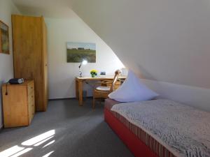 a bedroom with a bed and a desk with a chair at Unterm Reetdach in Born