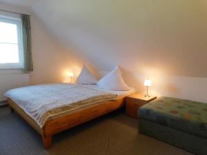 a bedroom with a bed with two lamps and a ottoman at Unterm Reetdach in Born