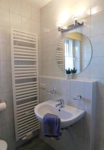 a white bathroom with a sink and a mirror at Unterm Reetdach in Born