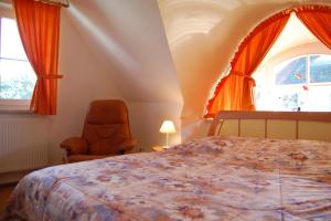 a bedroom with a bed and a chair and windows at Boddenhus in Born