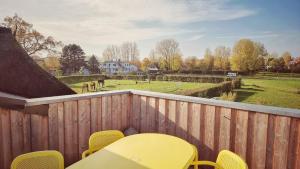 a deck with yellow chairs and a view of a field at Ferienhaus La Mer in Ahrenshoop