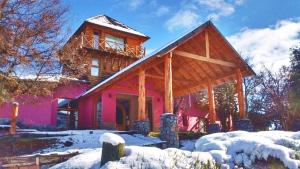 a pink house with snow on the ground at Nuevo Puerto Malen in Villa Pehuenia