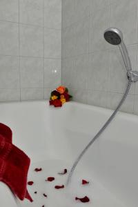 a bath tub with a shower and flowers on the floor at Schipperhus in Born