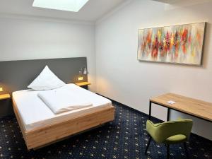 a bedroom with a bed and a desk and a painting at stadthotel miya in Bad Mergentheim