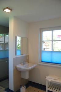 a white bathroom with a sink and two windows at Min Droom in Wustrow +5 photos