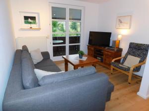 a living room with a blue couch and a television at Malergarten 14 in Ahrenshoop