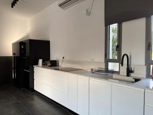 a kitchen with white cabinets and a black refrigerator at Aharon boutique suite in Pardes H̱anna