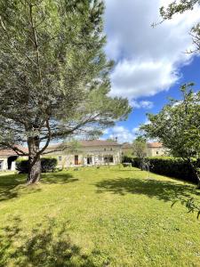 a large house with a tree in the yard at La maison de La Combe in Parzac