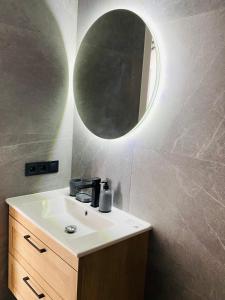 a bathroom with a sink and a round mirror at Золотий Бугаз корп5 апарт3 in Odesa +5 photos