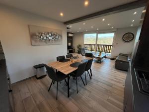 a dining room and living room with a table and chairs at Le Chalet de la belle vue in Fouchy
