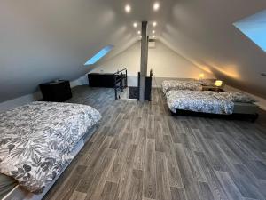 a attic bedroom with two beds and wooden floors at Le Chalet de la belle vue in Fouchy