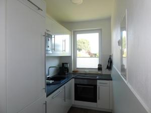 a white kitchen with a sink and a window at Sanddornhus in Ahrenshoop